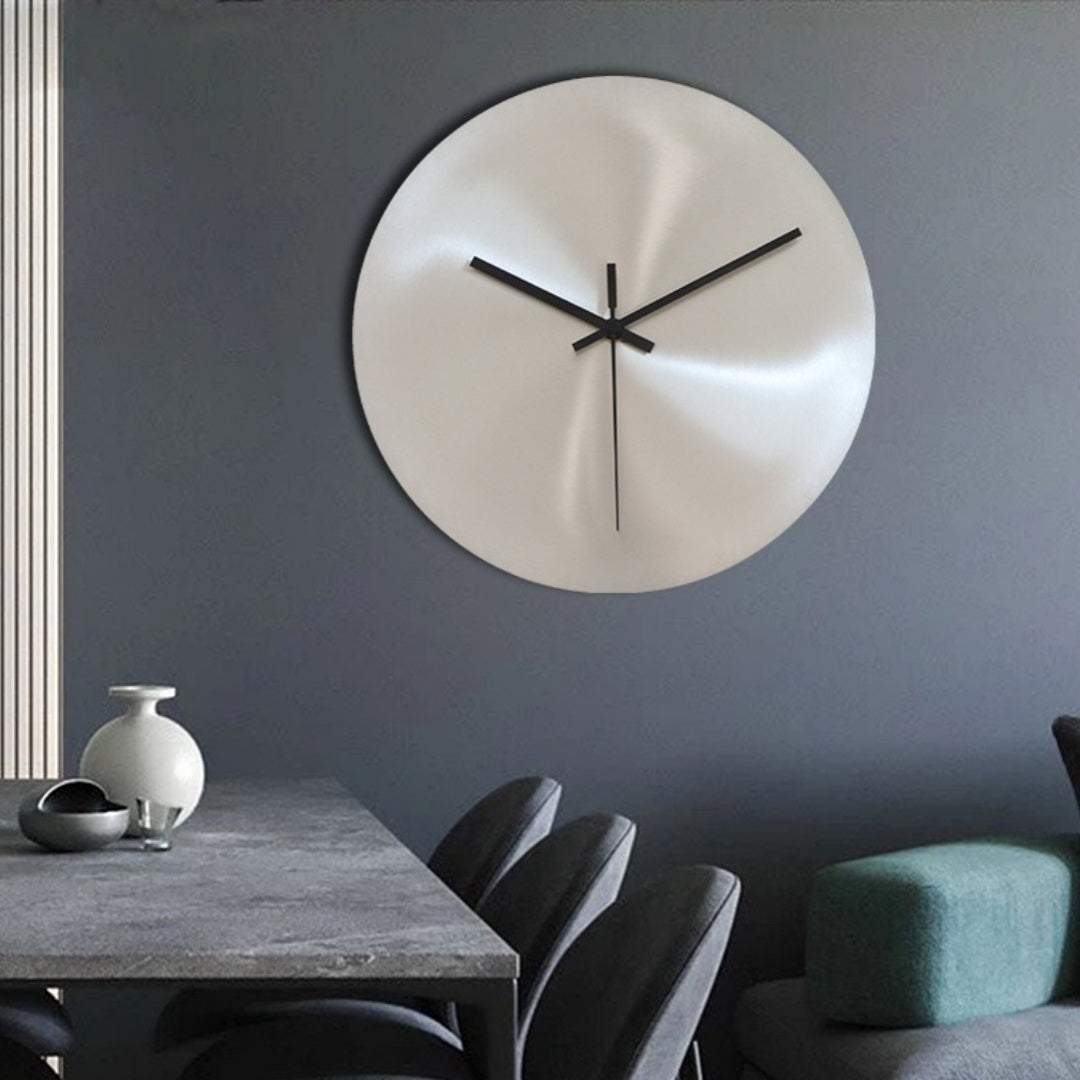 Round wall clock on a gray wall with a dining table and chairs in the foreground.