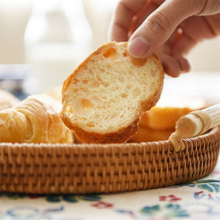 Hand picking a slice of bread from a basket on a patterned tablecloth
