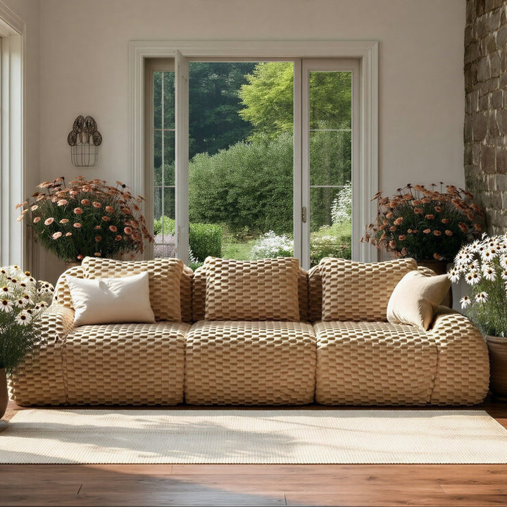 Living room with a woven sofa, potted plants, and large windows.