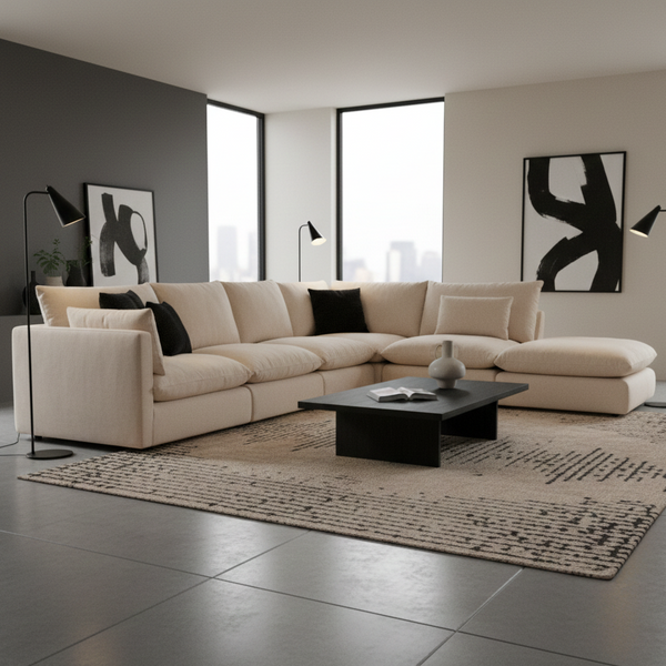 Modern living room with a beige sectional sofa, black coffee table, and abstract art on a gray wall.